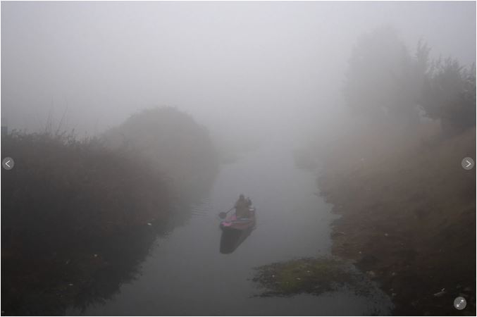 یک ماهیگیر کشمیری در یک صبح سرد در سرینگار، کشمیر تحت کنترل هند، پنج شنبه، 28 دسامبر 2023، قایق خود را در دریاچه دال احاطه شده با مه غلیظ احاطه کرده است.